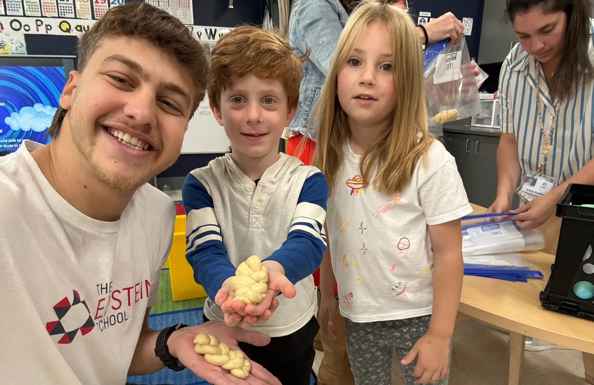 2025-2026 Shinshinim poses with two children, holding challah bread