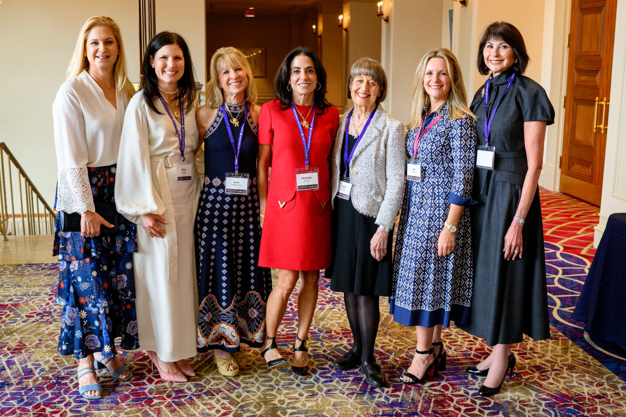 Seven women smile and pose together at Jewish Federation of Greater Atlanta's Lion of Judah & Pomegranate Luncheon.