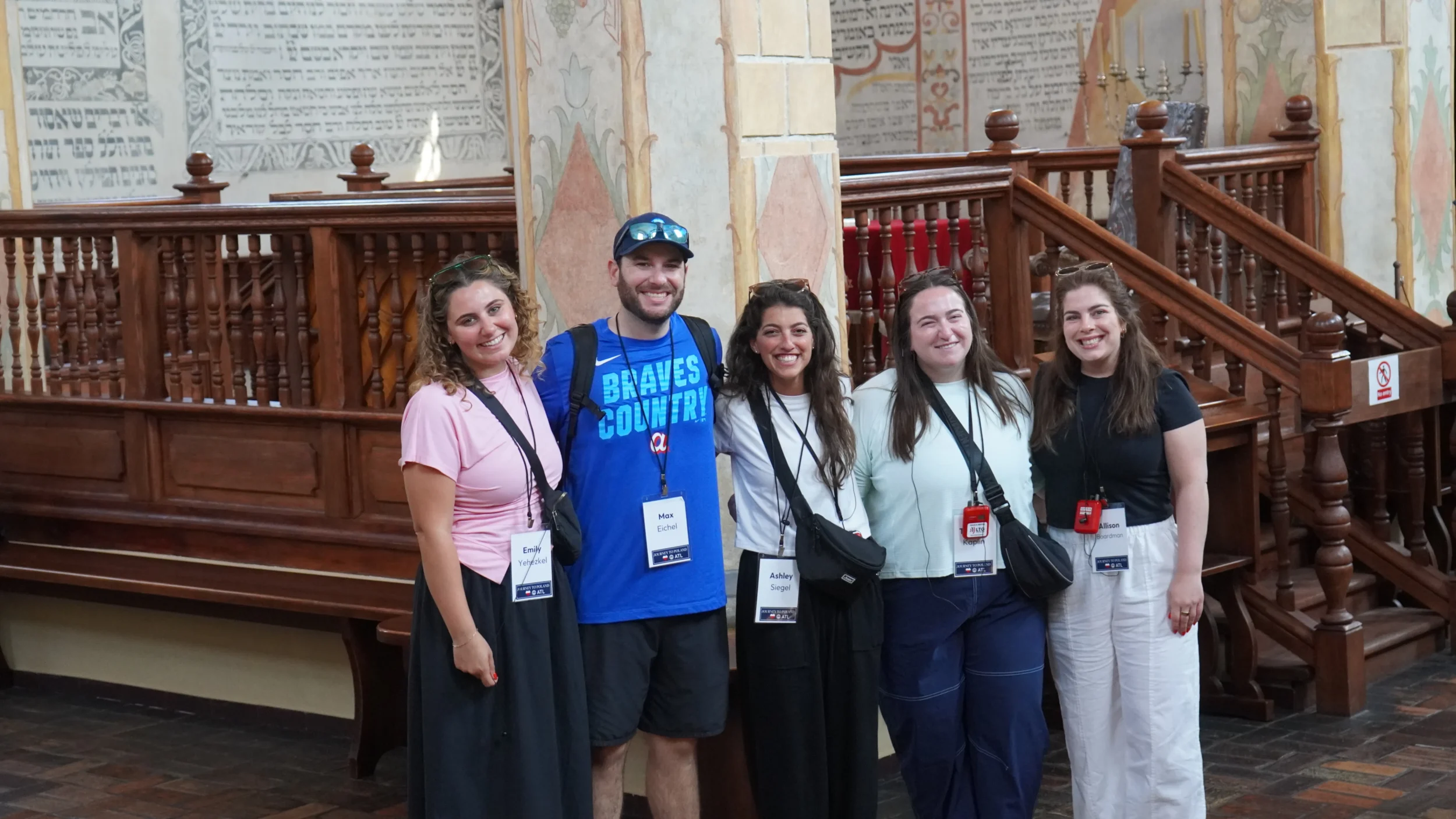 Five participants on the Young Leadership Division (YLD) Journey to Poland pose together inside a historic synagogue during the June 2026 mission.