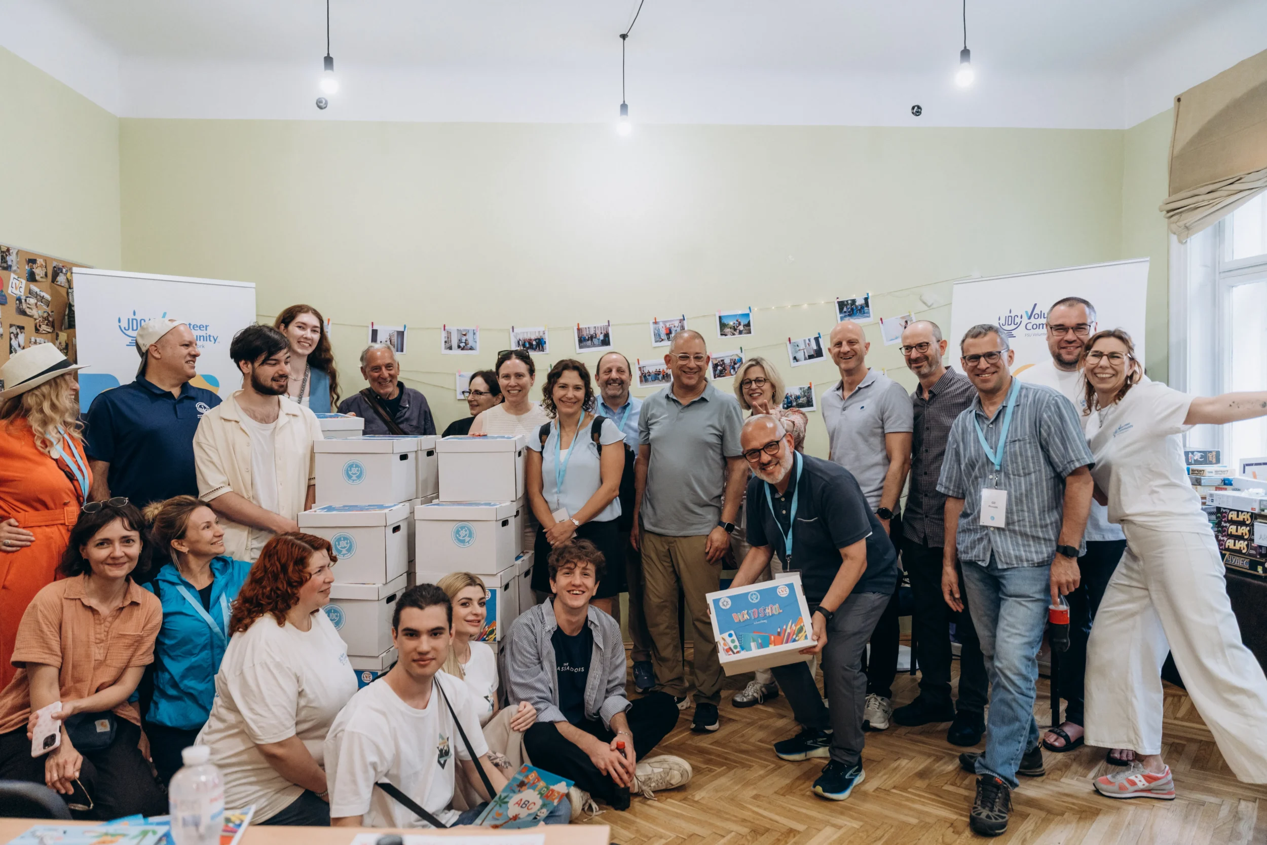 Renee Kutner, President & CEO of Jewish Federation of Greater Atlanta, joins JDC study mission participants and local community members for a group photo beside boxes of supplies at a JDC Volunteer Community site.