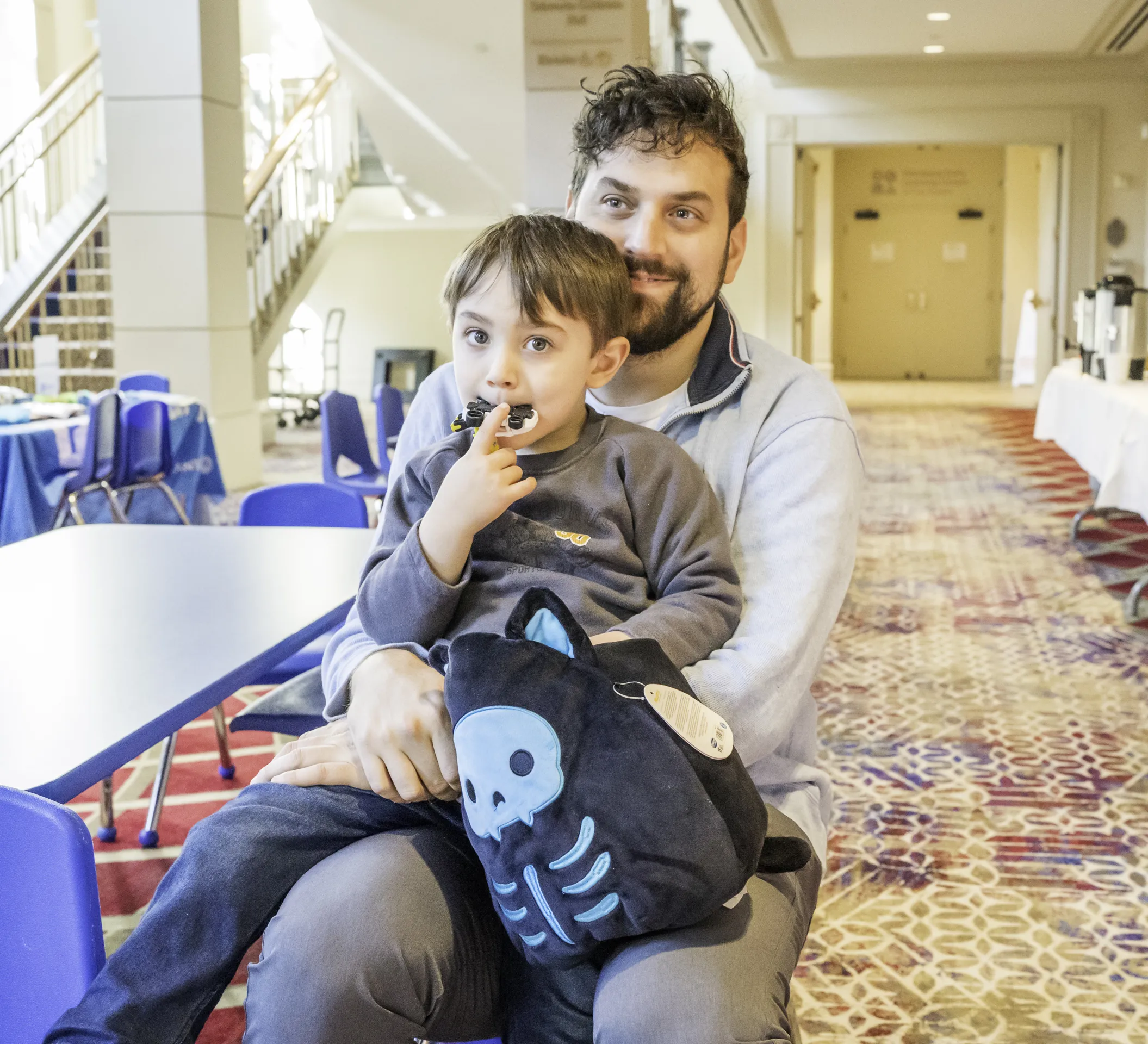 Son sits on his dads lap, eating a sweet treat