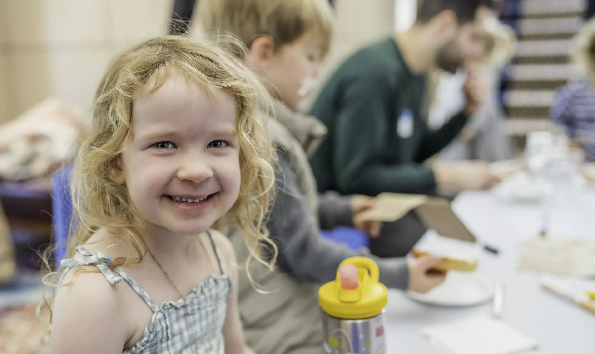Little girl wearing green plaid dress, smiles at camera