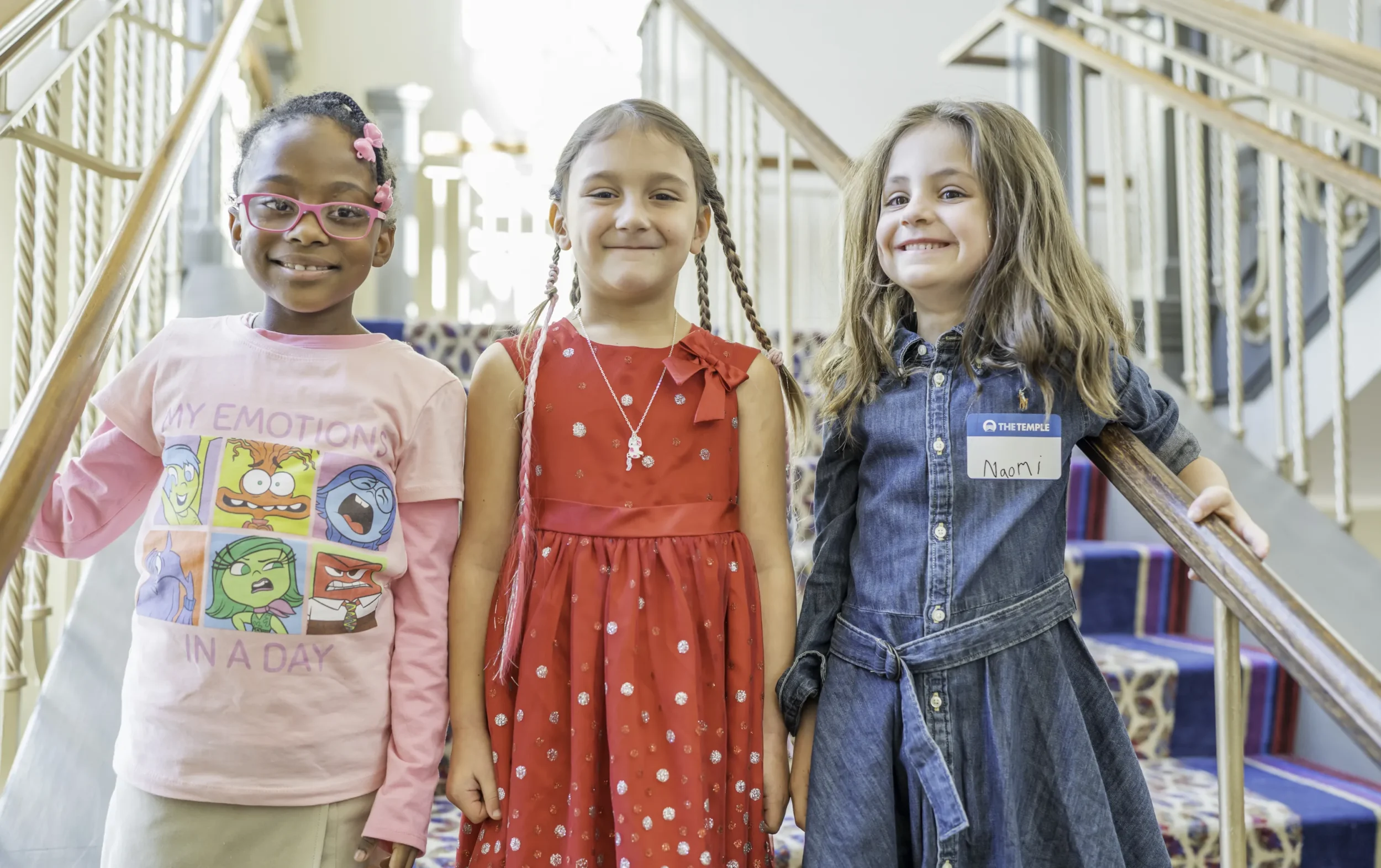 Three girls smiling, on staircase, at PJ Library event