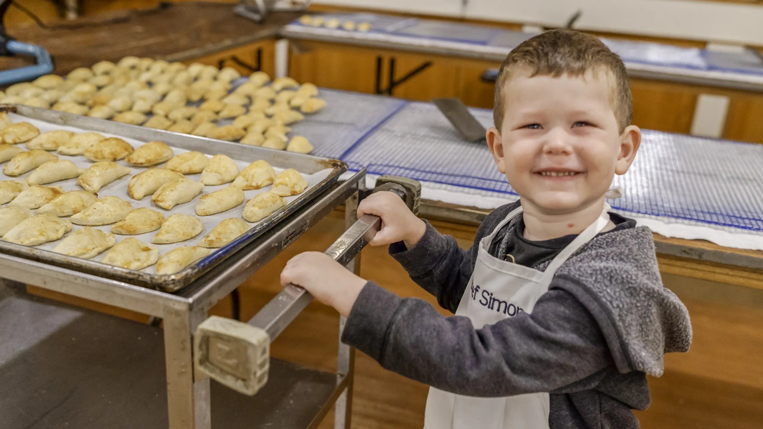 Jewish boy smiles at camera and pushes cart of bureka