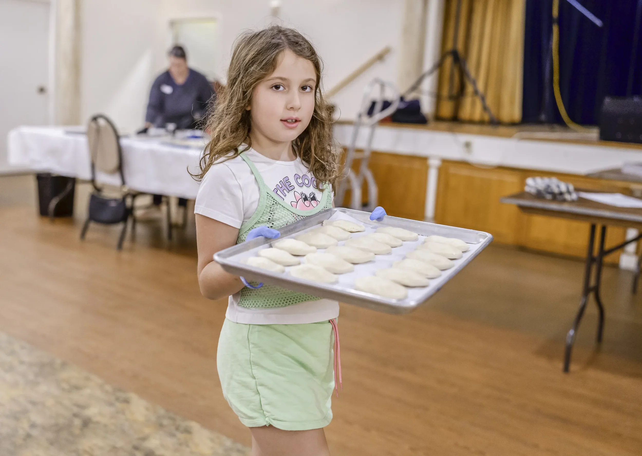 Jewish girl carrying a sheet pan full of bureka