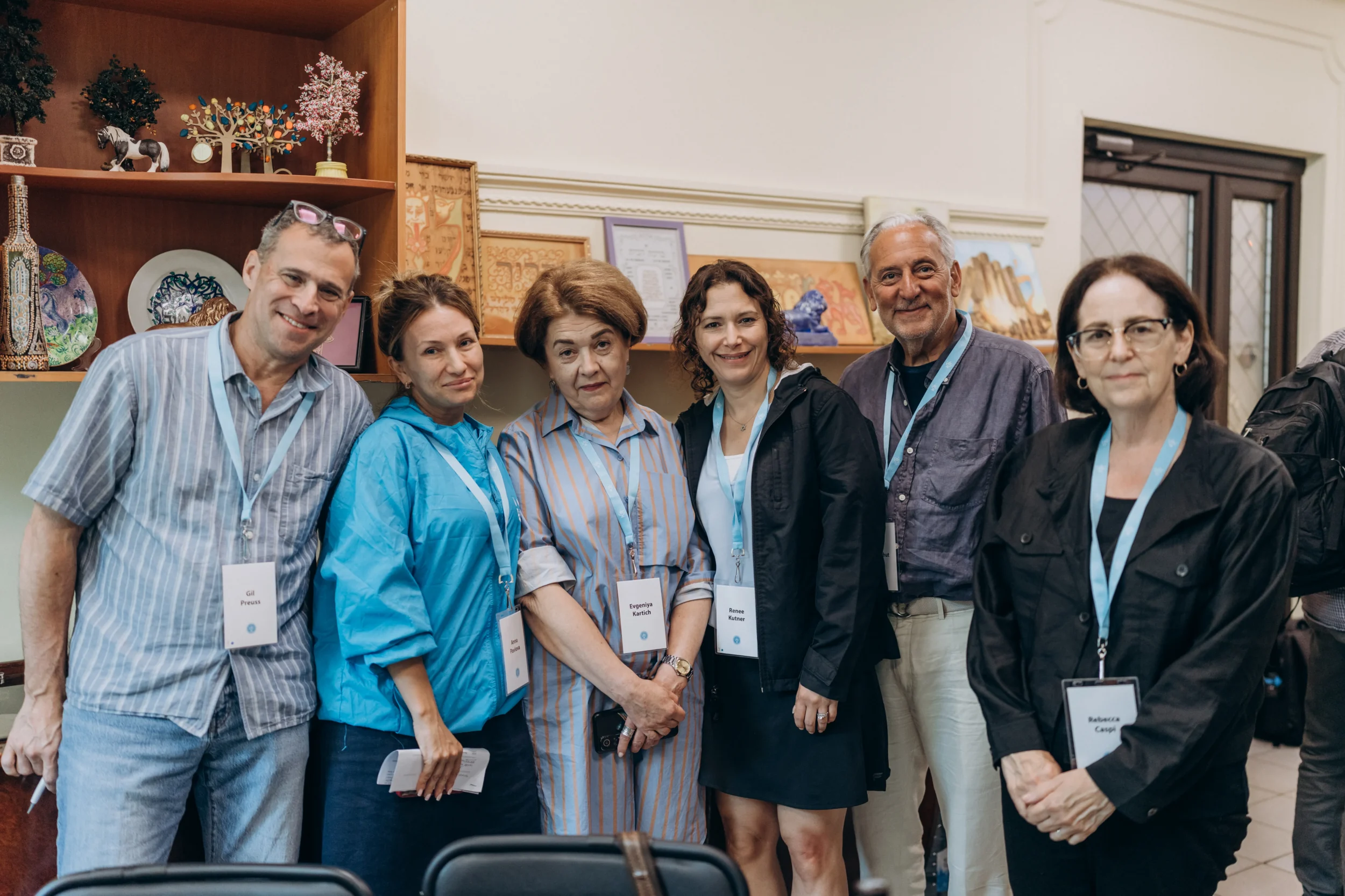 Renee Kutner, President & CEO of Jewish Federation of Greater Atlanta, stands with fellow participants during a JDC study mission, gathered in front of shelves displaying Jewish art and community items.