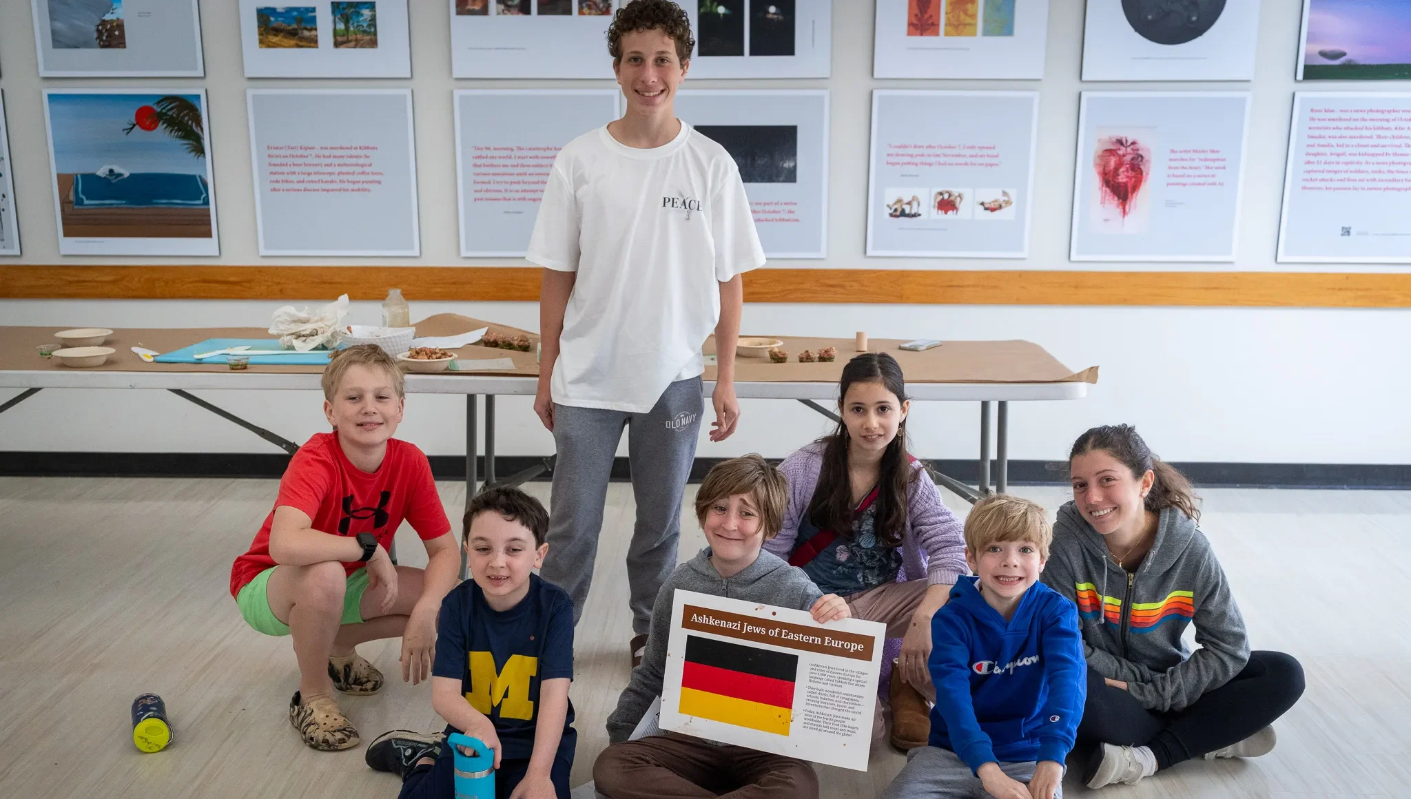 Children and teen leaders from Congregation Shearith Israel pose together during a Jewish education activity, with one student holding a project about Ashkenazi Jews of Eastern Europe.
