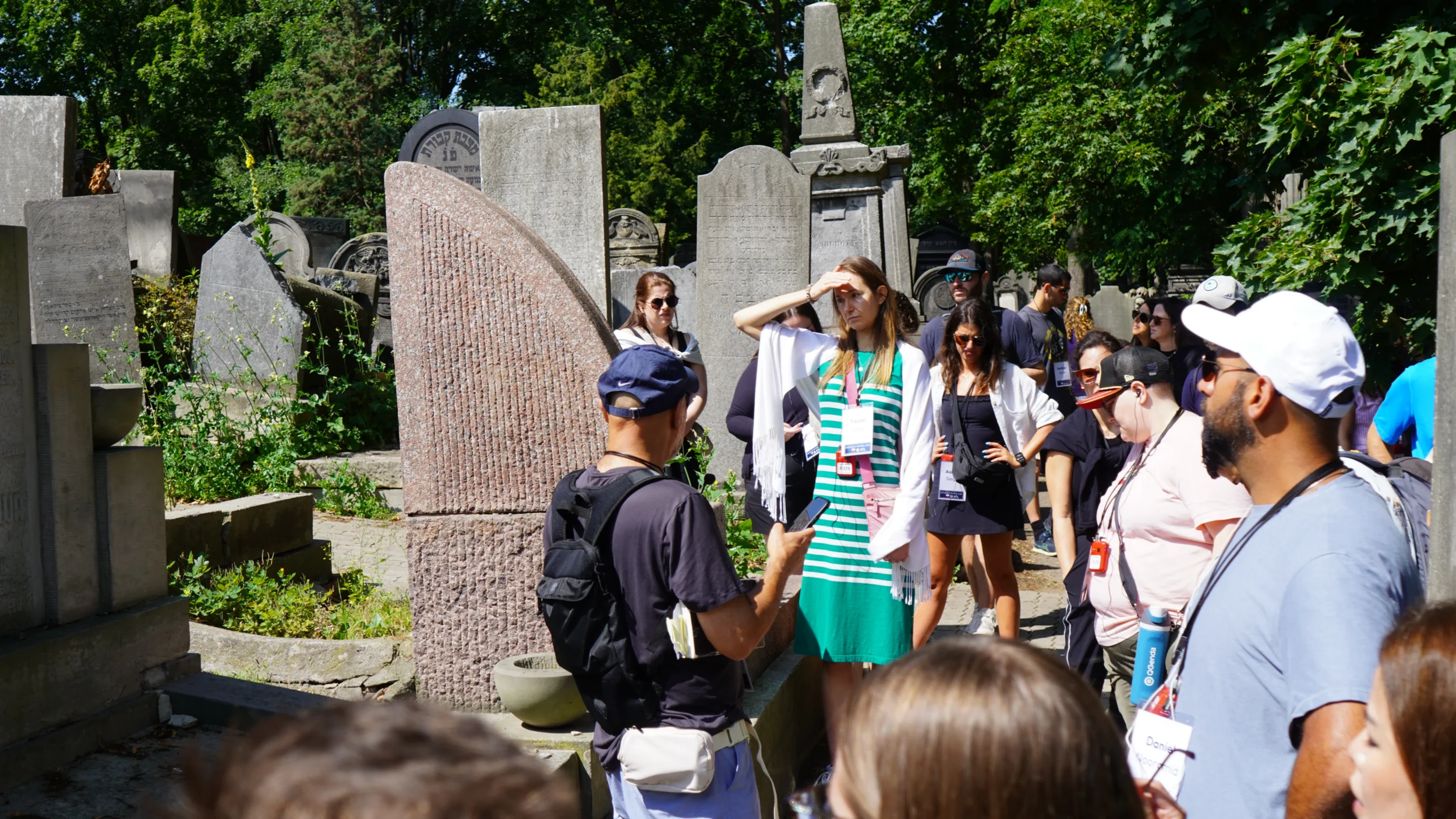 YLD Journey to Poland participants listen to a guide among historic Jewish gravestones in a cemetery.